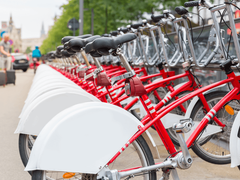 Rij rode huurfietsen langs een gracht in de stad