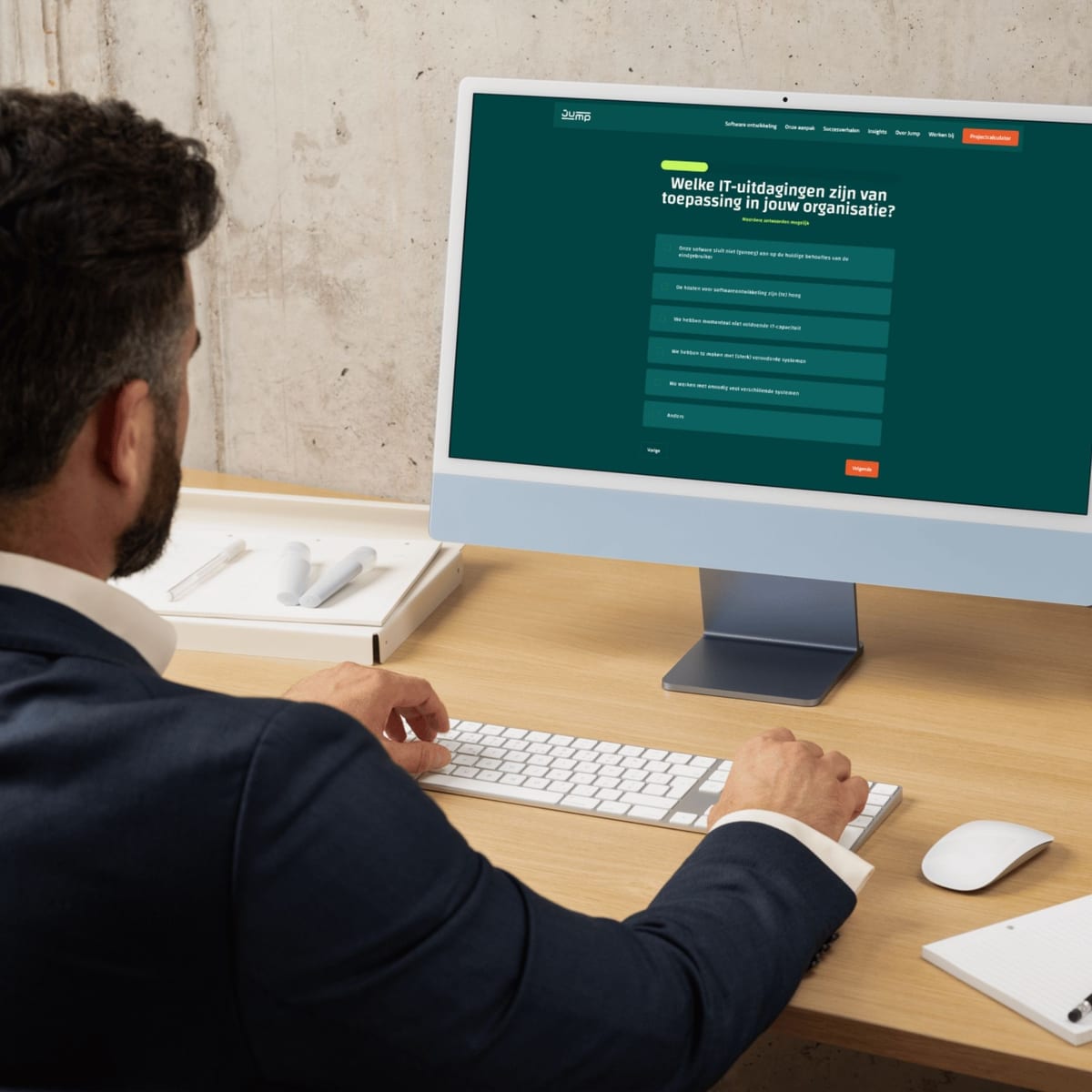 Man achter een iMac met de vragenlijst 'Welke IT-uitdagingen zijn van toepassing in jouw organisatie?'