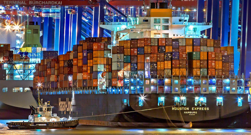 Containerschip aan de kade van een containerterminal, 's avonds verlicht